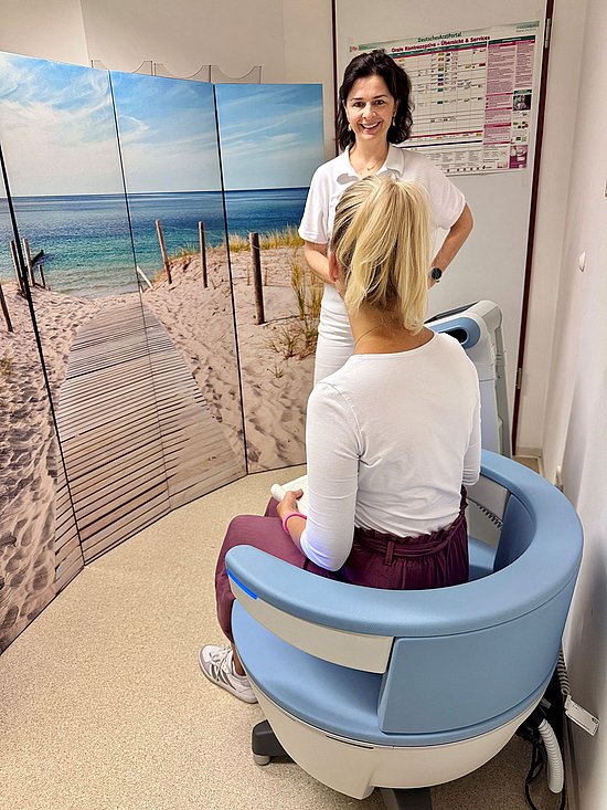 Patient sitting on the BTL EMSELLA chair in Regensburg with Dr. Jánky standing in front of her, smiling.