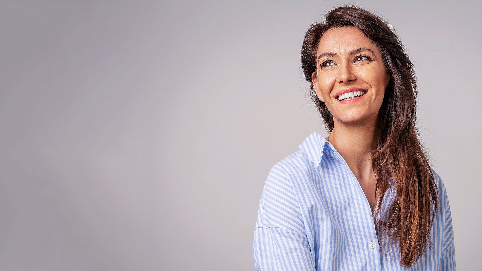 Smiling woman standing in front of a grey background